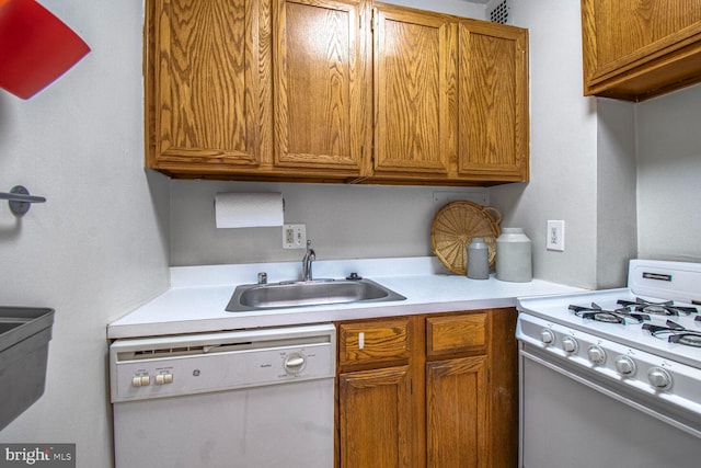 kitchen with brown cabinets, white appliances, light countertops, and a sink