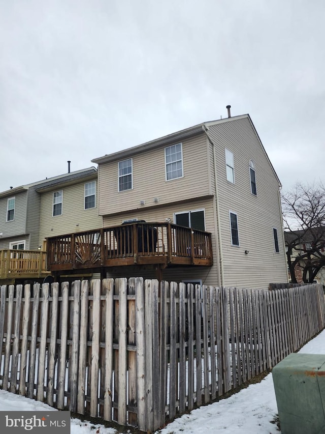 snow covered back of property with a wooden deck