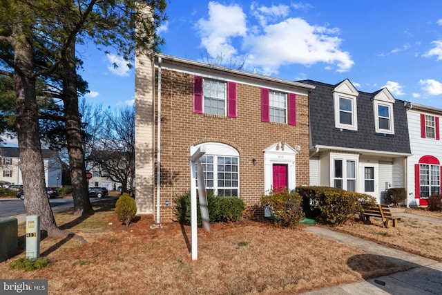 multi unit property featuring a shingled roof and brick siding