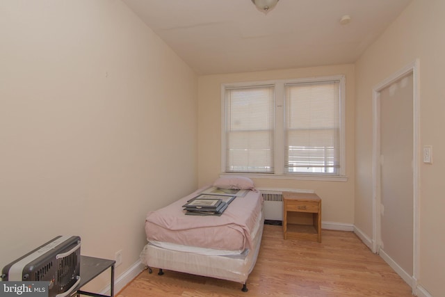 bedroom featuring radiator heating unit and light wood-type flooring