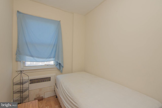 bedroom featuring radiator and hardwood / wood-style floors