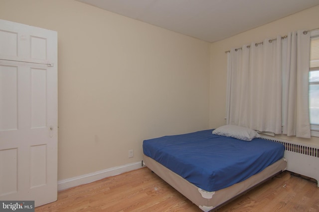 bedroom with hardwood / wood-style flooring and radiator heating unit