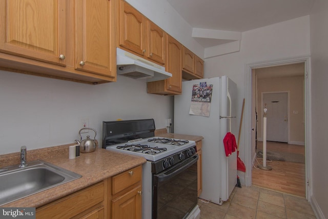 kitchen featuring gas range, white fridge, and sink