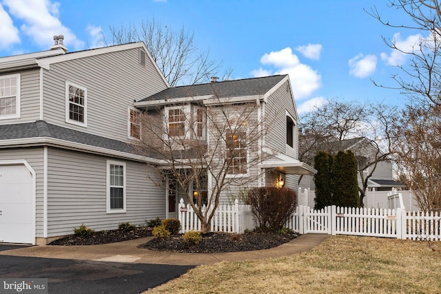 view of side of property with a garage, a shingled roof, and a fenced front yard