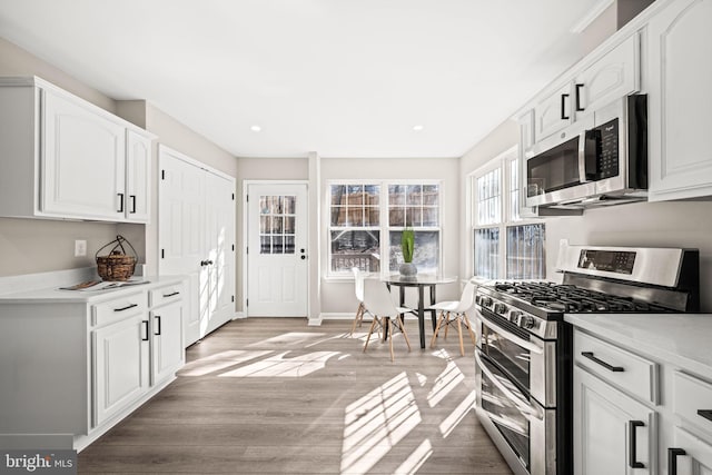 kitchen featuring appliances with stainless steel finishes, light hardwood / wood-style flooring, and white cabinetry