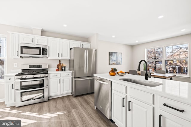 kitchen featuring sink, stainless steel appliances, white cabinetry, and a wealth of natural light