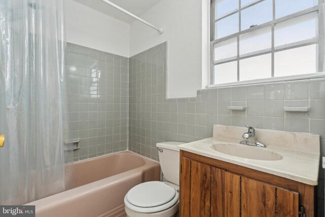 full bathroom with toilet, vanity, shower / bath combo with shower curtain, and tile walls