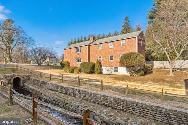 view of home's exterior featuring brick siding, a chimney, and a fenced backyard