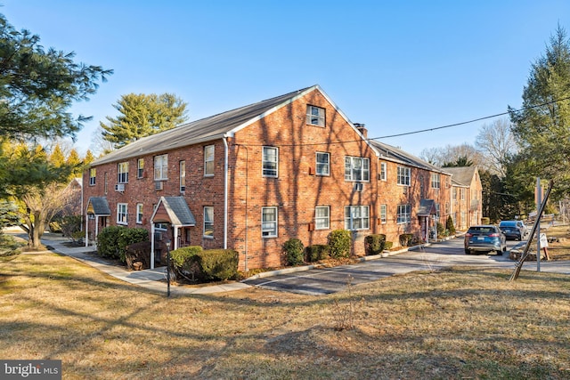 view of side of property with brick siding, a lawn, and a chimney