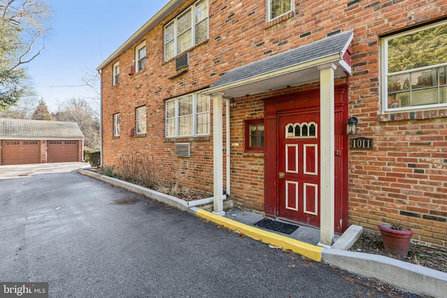 doorway to property featuring brick siding and a detached garage