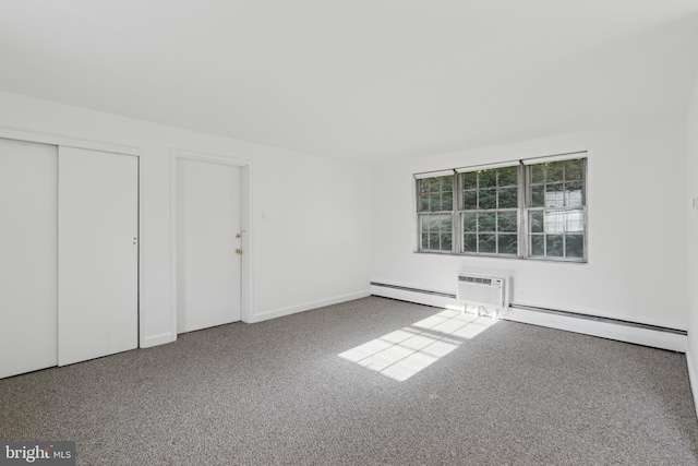 unfurnished bedroom featuring a wall unit AC, carpet, a baseboard heating unit, and a closet