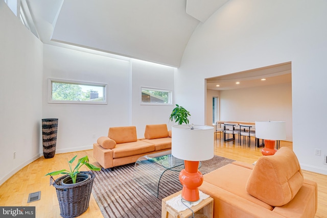 living area featuring high vaulted ceiling, baseboards, and wood finished floors