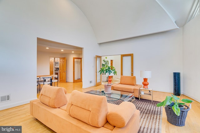 living area with baseboards, visible vents, wood finished floors, high vaulted ceiling, and recessed lighting