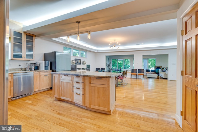 kitchen featuring a raised ceiling, stainless steel appliances, light brown cabinets, and glass insert cabinets