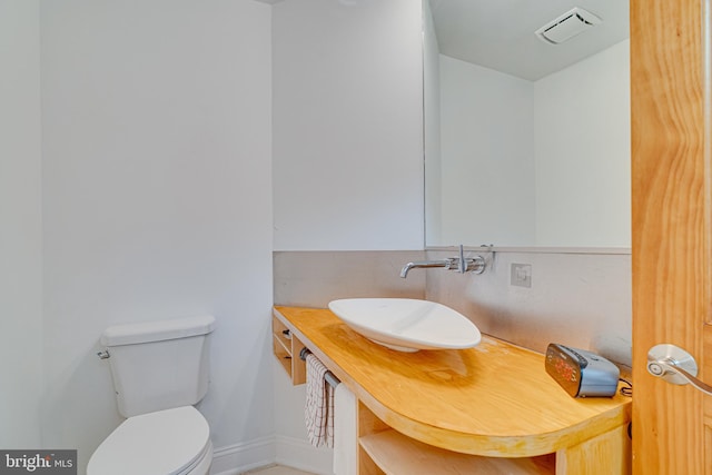 bathroom with toilet, a sink, visible vents, and baseboards