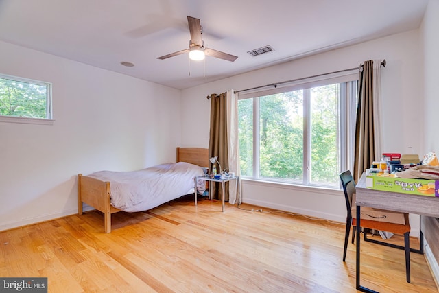 bedroom featuring light wood-style floors, baseboards, visible vents, and a ceiling fan