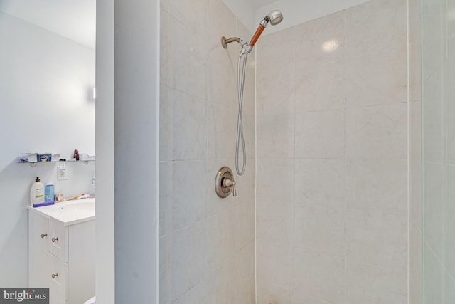 bathroom with tiled shower and vanity