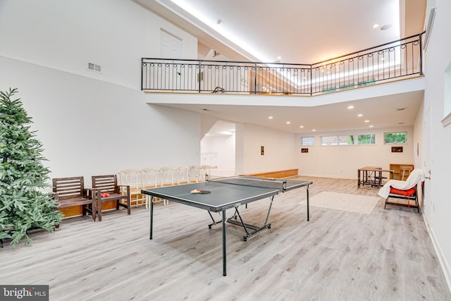 recreation room with baseboards, visible vents, a high ceiling, light wood-style floors, and recessed lighting