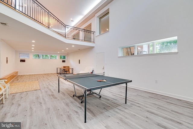 game room featuring light wood finished floors, recessed lighting, a high ceiling, and baseboards