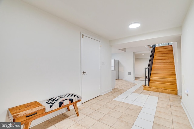 interior space with baseboards, stairway, and light tile patterned flooring