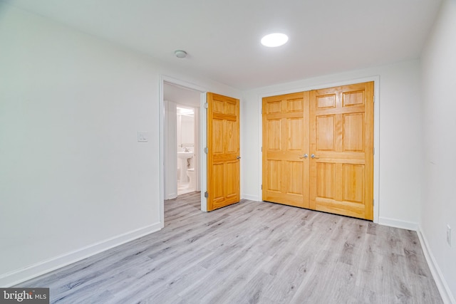 unfurnished bedroom featuring light wood-style floors, a closet, and baseboards