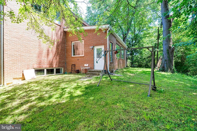 rear view of property featuring brick siding and a lawn