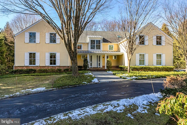 view of front of house featuring a standing seam roof, brick siding, metal roof, and stucco siding