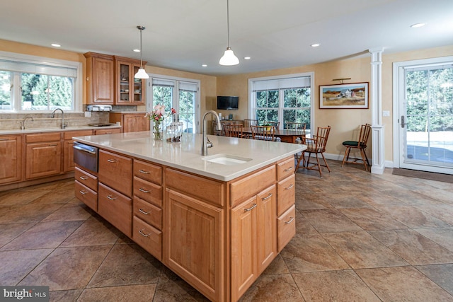 kitchen featuring a warming drawer, a sink, a center island with sink, and a healthy amount of sunlight