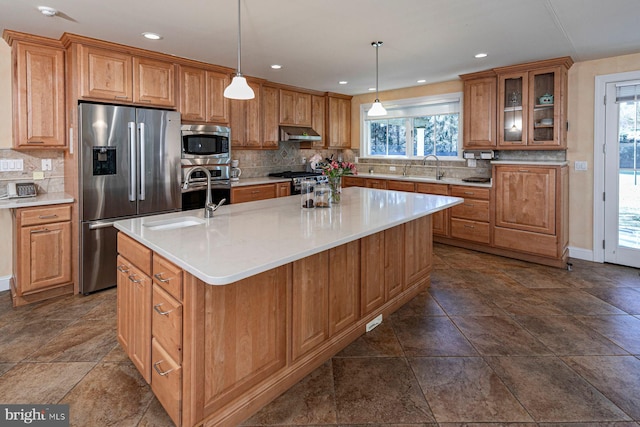 kitchen featuring an island with sink, under cabinet range hood, stainless steel appliances, and a wealth of natural light