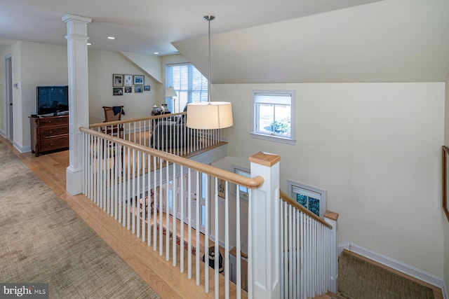 staircase with decorative columns, baseboards, vaulted ceiling, and wood finished floors