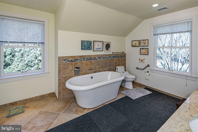 full bath with a soaking tub, plenty of natural light, visible vents, and vaulted ceiling