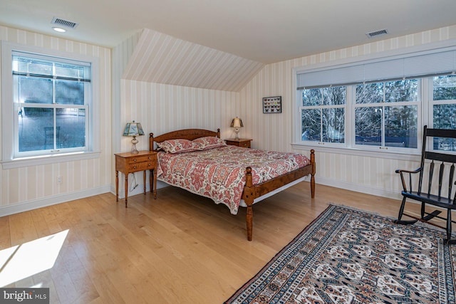 bedroom with light wood-type flooring, wallpapered walls, baseboards, and visible vents