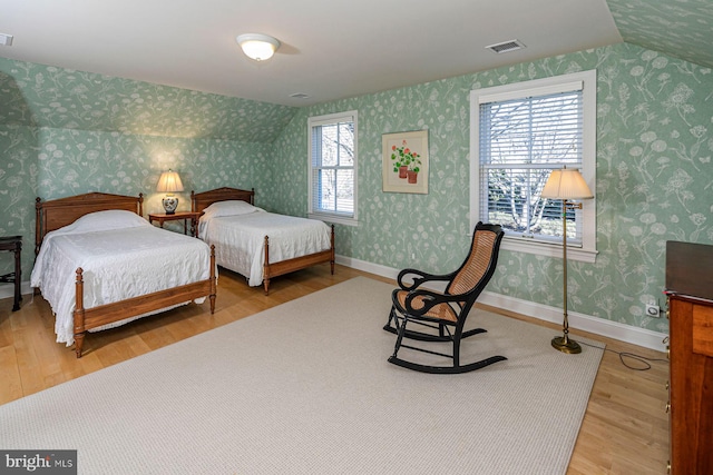 bedroom featuring wallpapered walls, baseboards, and wood finished floors