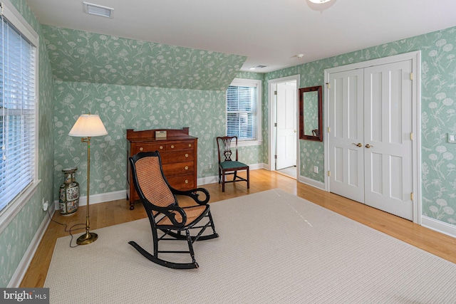 living area with visible vents and wallpapered walls