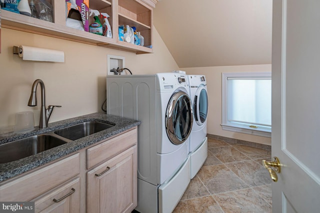 washroom with cabinet space, washer and clothes dryer, and a sink