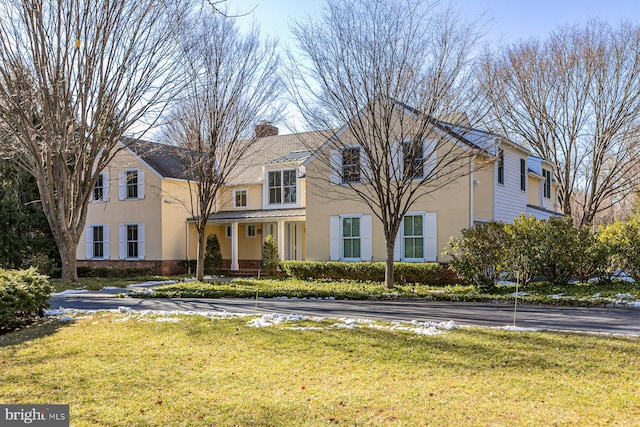 view of front of home featuring a front yard, a chimney, and stucco siding