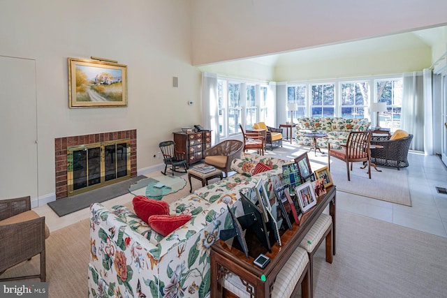 tiled living area with visible vents, a fireplace, a towering ceiling, and baseboards