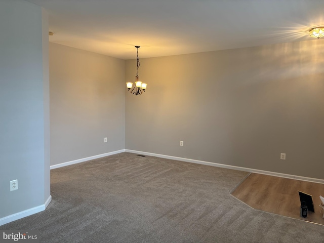 unfurnished room with baseboards, carpet flooring, visible vents, and a notable chandelier