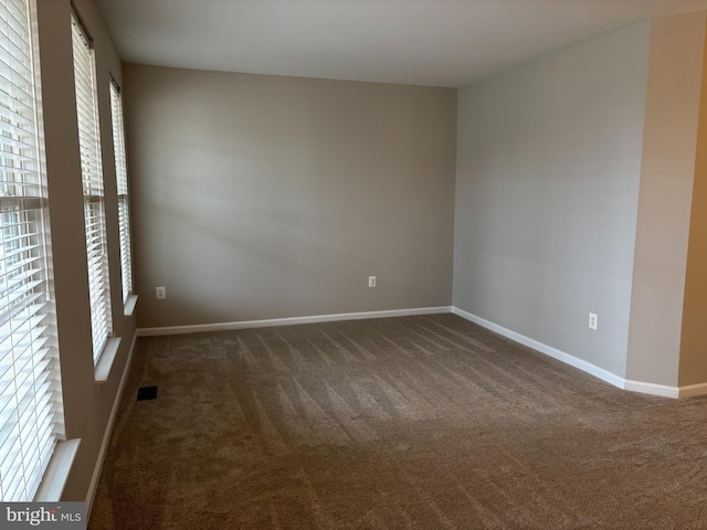 spare room with carpet, visible vents, and baseboards