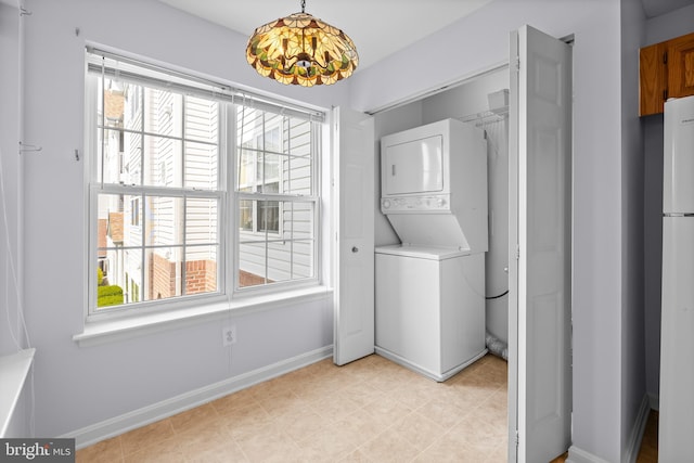 laundry area featuring stacked washer and clothes dryer, baseboards, and laundry area