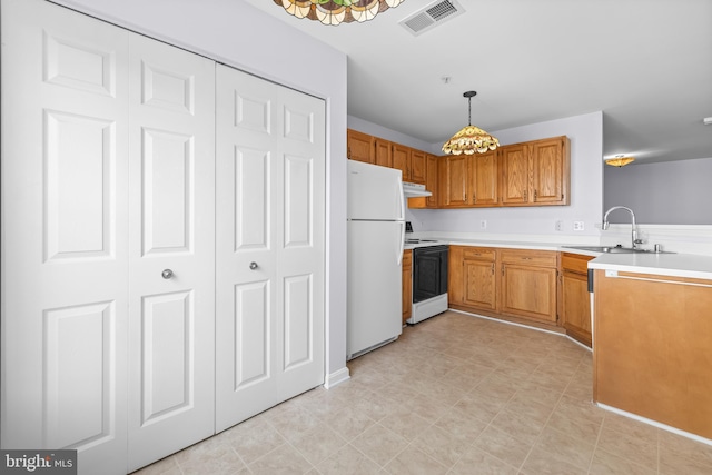 kitchen with a sink, visible vents, freestanding refrigerator, range with electric stovetop, and light countertops
