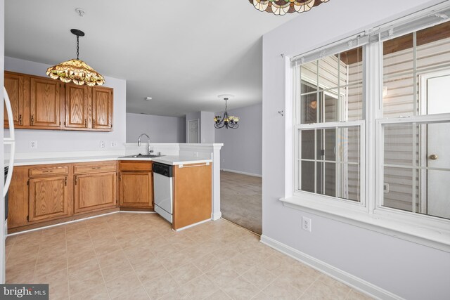 kitchen with a peninsula, stainless steel dishwasher, a sink, a notable chandelier, and pendant lighting