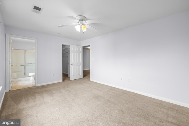 unfurnished bedroom with a closet, a spacious closet, carpet floors, baseboards, and visible vents