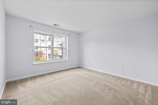 empty room featuring baseboards, visible vents, and carpet flooring