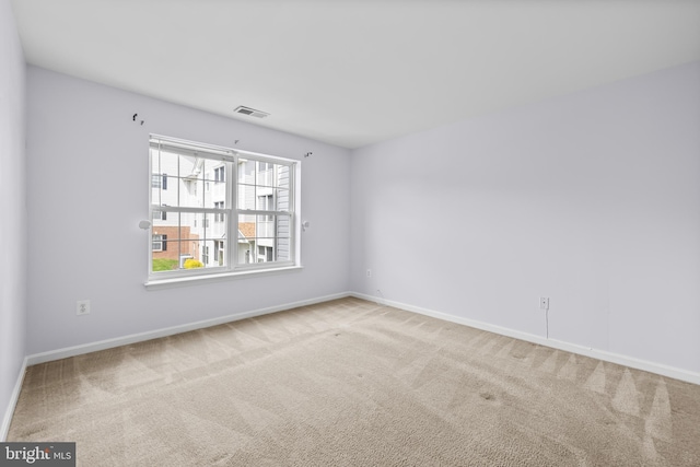 unfurnished room featuring baseboards, visible vents, and carpet