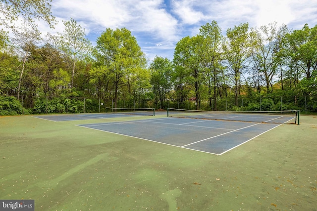 view of tennis court with community basketball court and fence