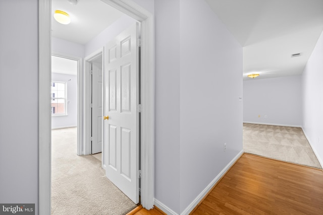 corridor featuring visible vents, baseboards, and carpet