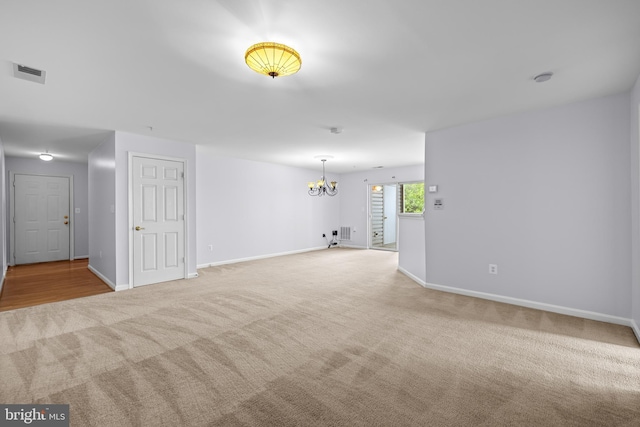 unfurnished room featuring light colored carpet, baseboards, a chandelier, and visible vents