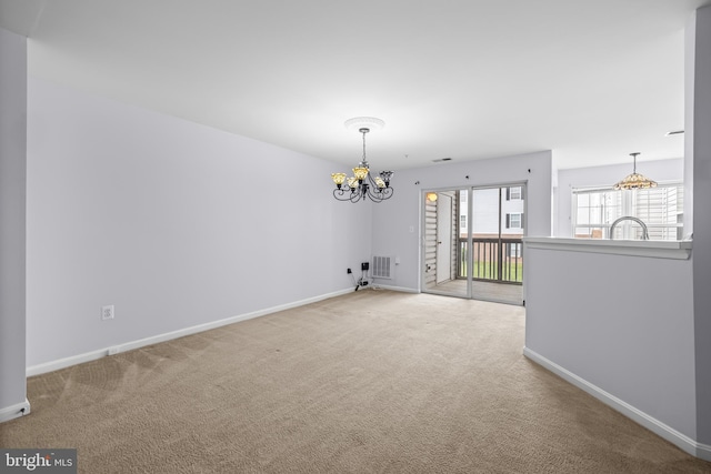 carpeted spare room with visible vents, baseboards, a sink, and a notable chandelier