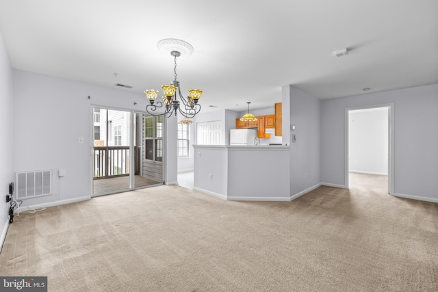 unfurnished living room with visible vents, light carpet, baseboards, and a notable chandelier